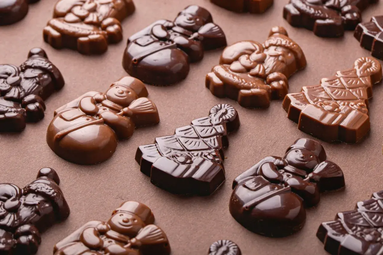 Chokladfigurer av tomtar och snögubbar, perfekt tempererad vit choklad för julens godsaker.