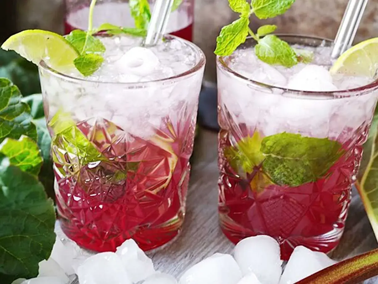 Två glas med rabarber mojito, is, mynta och lime. En uppfriskande sommardrink.