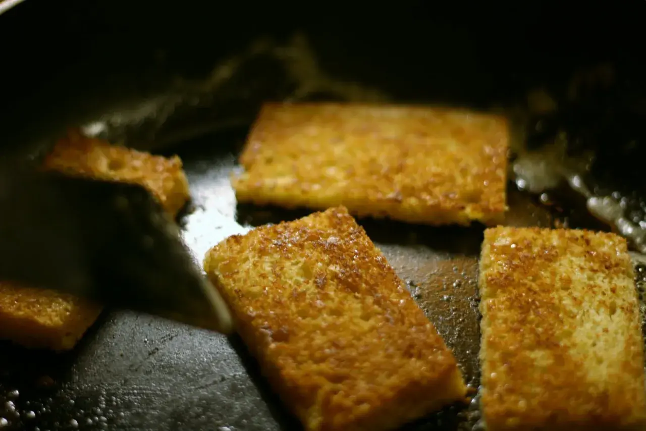 Gyldene skiver av brioche steker i en varm stekepanne. Snart redo att baka brioche!