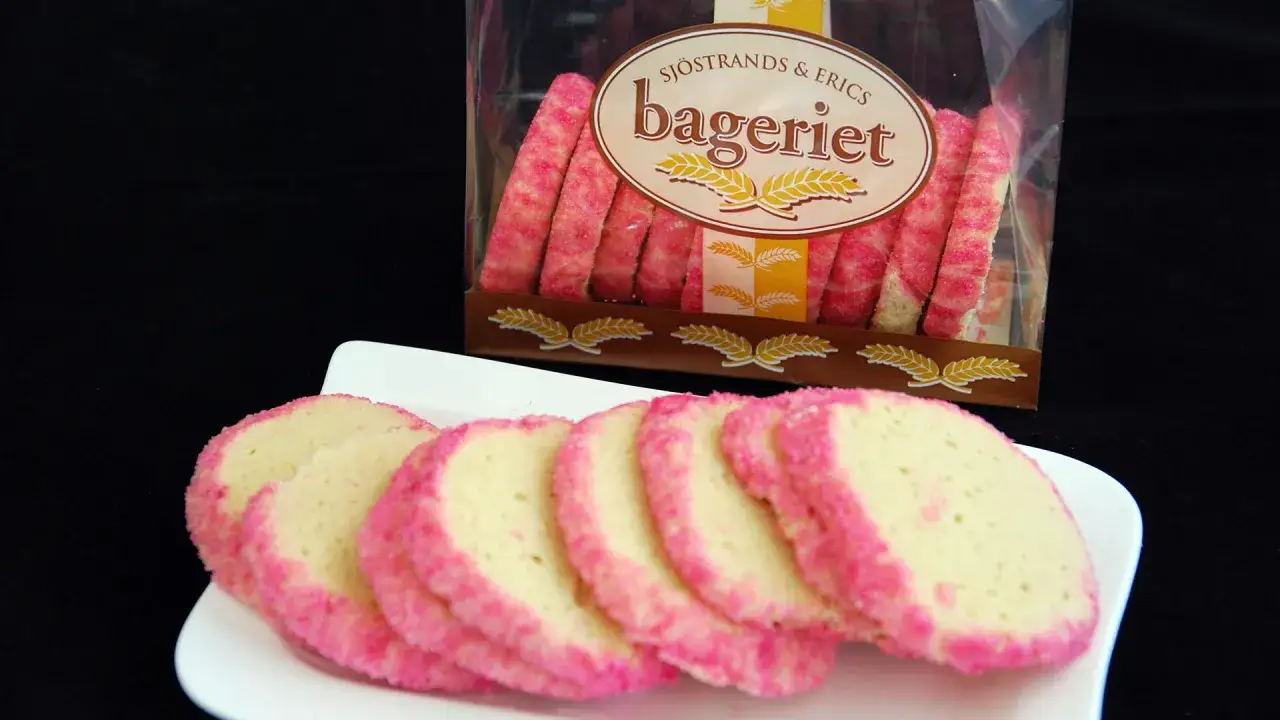 Skivade brysselkex med rosa str&ouml;ssel p&aring; en vit tallrik, bredvid en f&ouml;rpackning med fler kex. Ett enkelt brysselkex recept.