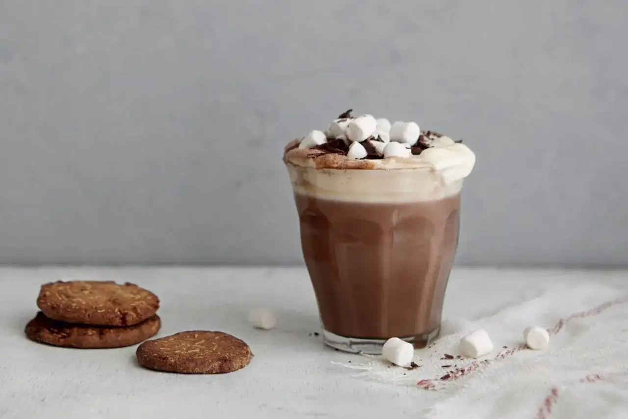 En h&auml;rlig varm choklad med fluffigt skum, marshmallows och chokladstr&ouml;ssel. Bredvid st&aring;r n&aring;gra krispiga kakor.