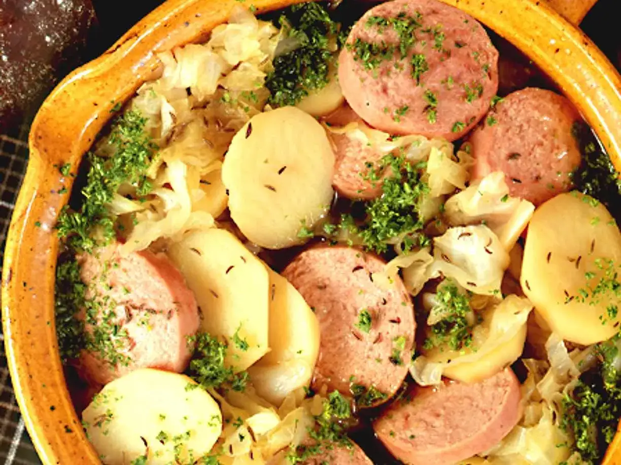 En värmande korvgryta med potatis, kål och persilja i en rustik keramikskål. En klassisk rätt som passar perfekt en kylig dag.