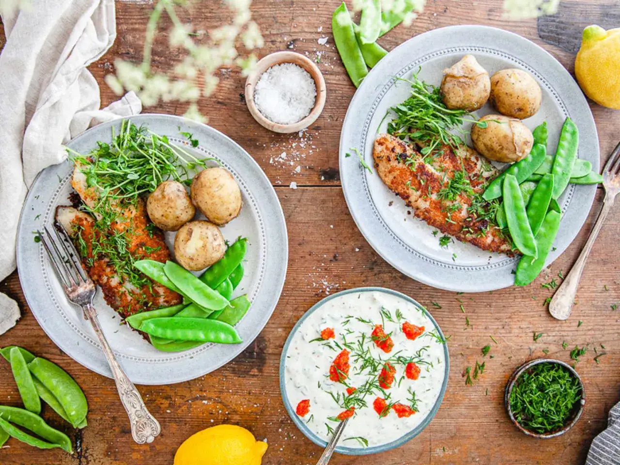 Tv&aring; tallrikar med panerad abborre, sm&aring;potatis och socker&auml;rtor. En sk&aring;l med roms&aring;s och en sk&aring;l med dill. Ett perfekt abborre recept f&ouml;r en h&auml;rlig middag.