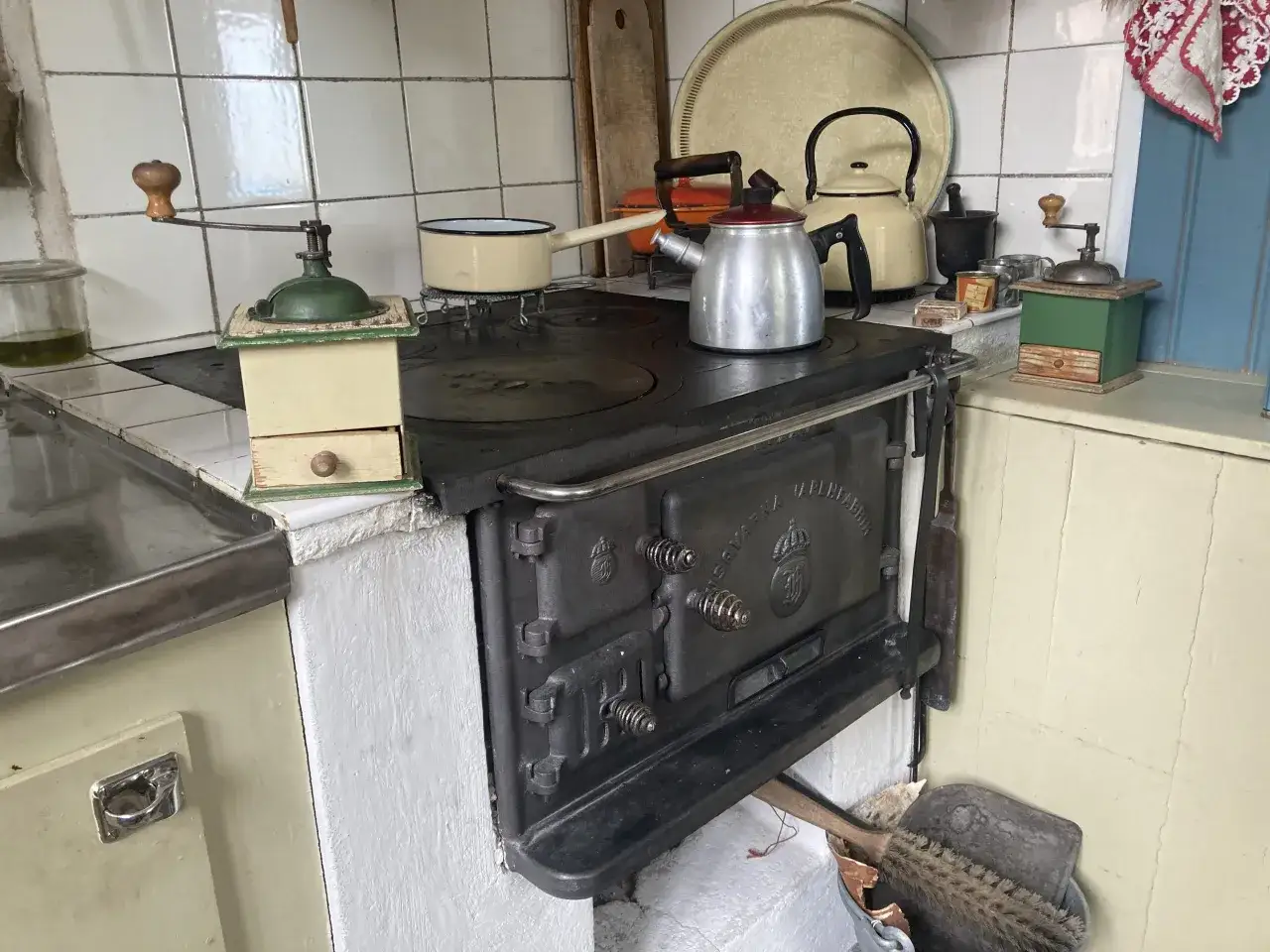 Gammaldags k&ouml;k med vedspis. En kastrull st&aring;r redo att koka kaffe. Kaffekvarnar och en gammal tekanna finns ocks&aring;.