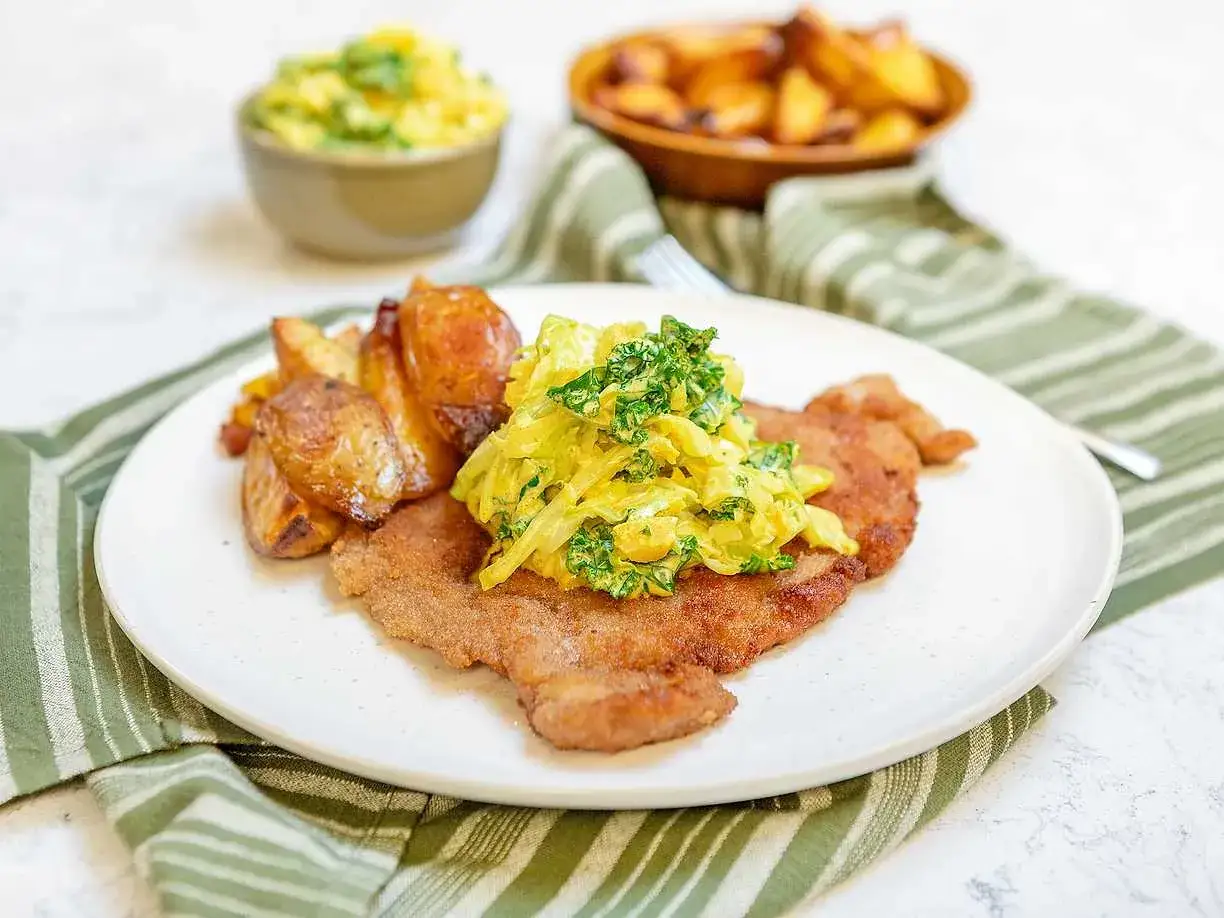 Krispig schnitzel med kr&auml;mig k&aring;lsallad och ugnsrostad potatis. Ett perfekt schnitzel recept f&ouml;r en god middag.