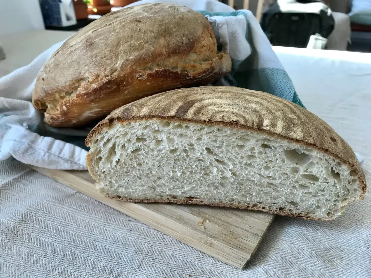 Tv&aring; nybakade levainbr&ouml;d, ett halvt uppskuret f&ouml;r att visa den luftiga inkr&aring;met. Perfekt att baka levain utan surdeg!