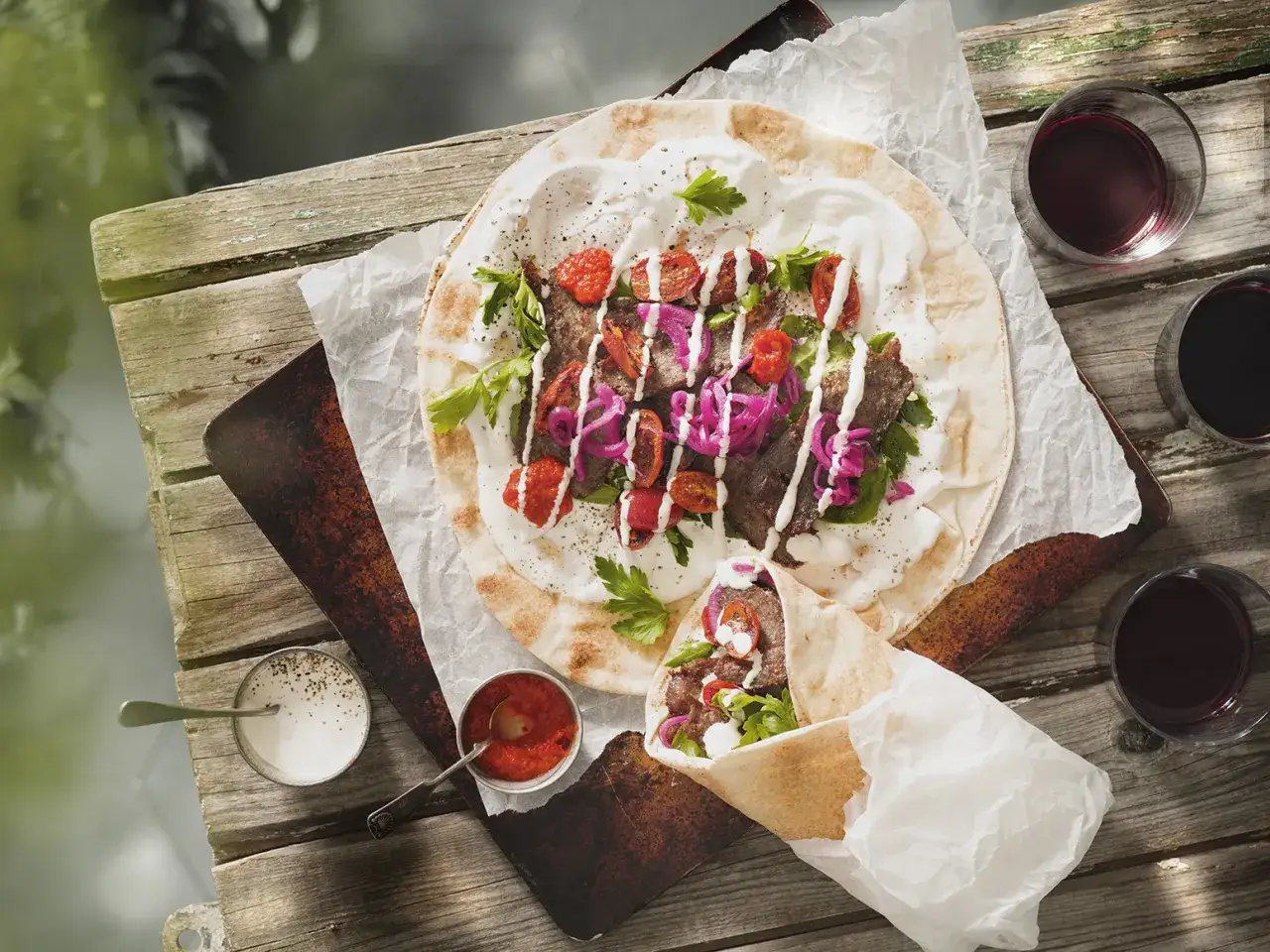 En l&auml;cker kyckling kebab p&aring; ett plattbr&ouml;d, toppad med tomater, r&ouml;dl&ouml;k och persilja. Serveras med s&aring;s och r&ouml;d s&aring;s.