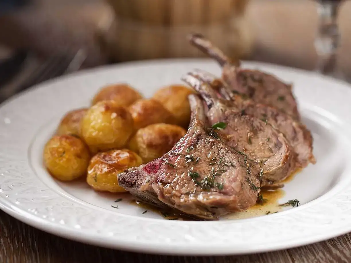 En tallrik med saftiga lammracks och sm&aring;, gyllene potatisar. Ett perfekt lammracks recept f&ouml;r en festlig middag.