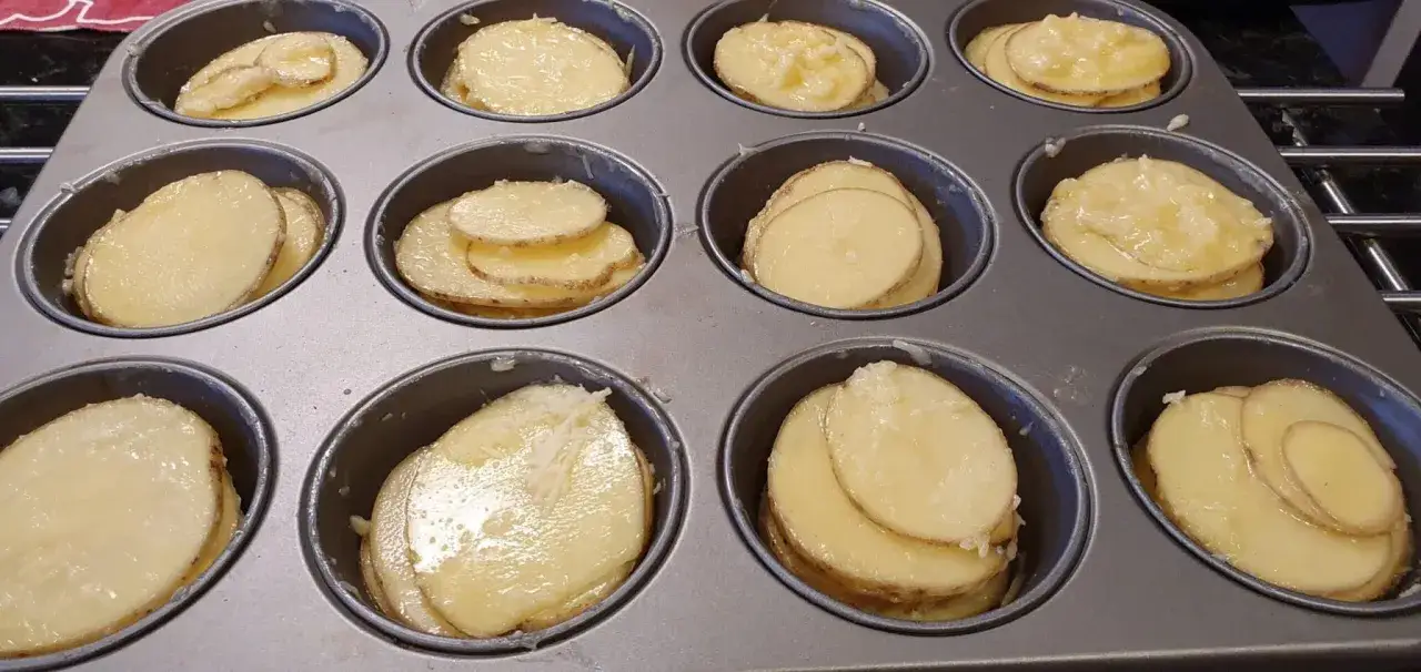 Tunna skivor av potatis i muffinsform, redo att bakas. Enkel och god r&auml;tt.