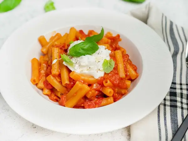 En krämig pasta med tomatsås och en generös klick burrata, perfekt för ett enkelt burrata recept. Garnerad med färsk basilika.